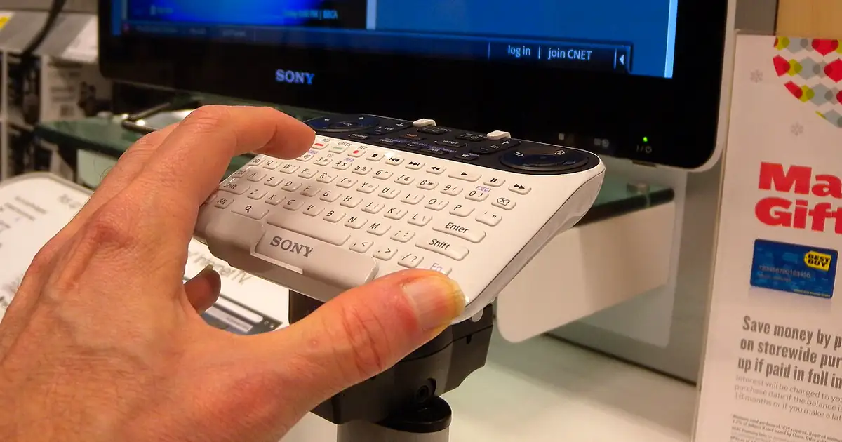 Main utilisant une télécommande clavier devant un téléviseur connecté Sony